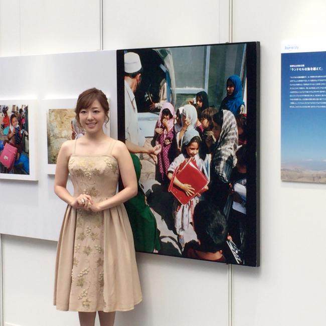 展示されたアフガニスタンの写真の前に立つ綾香